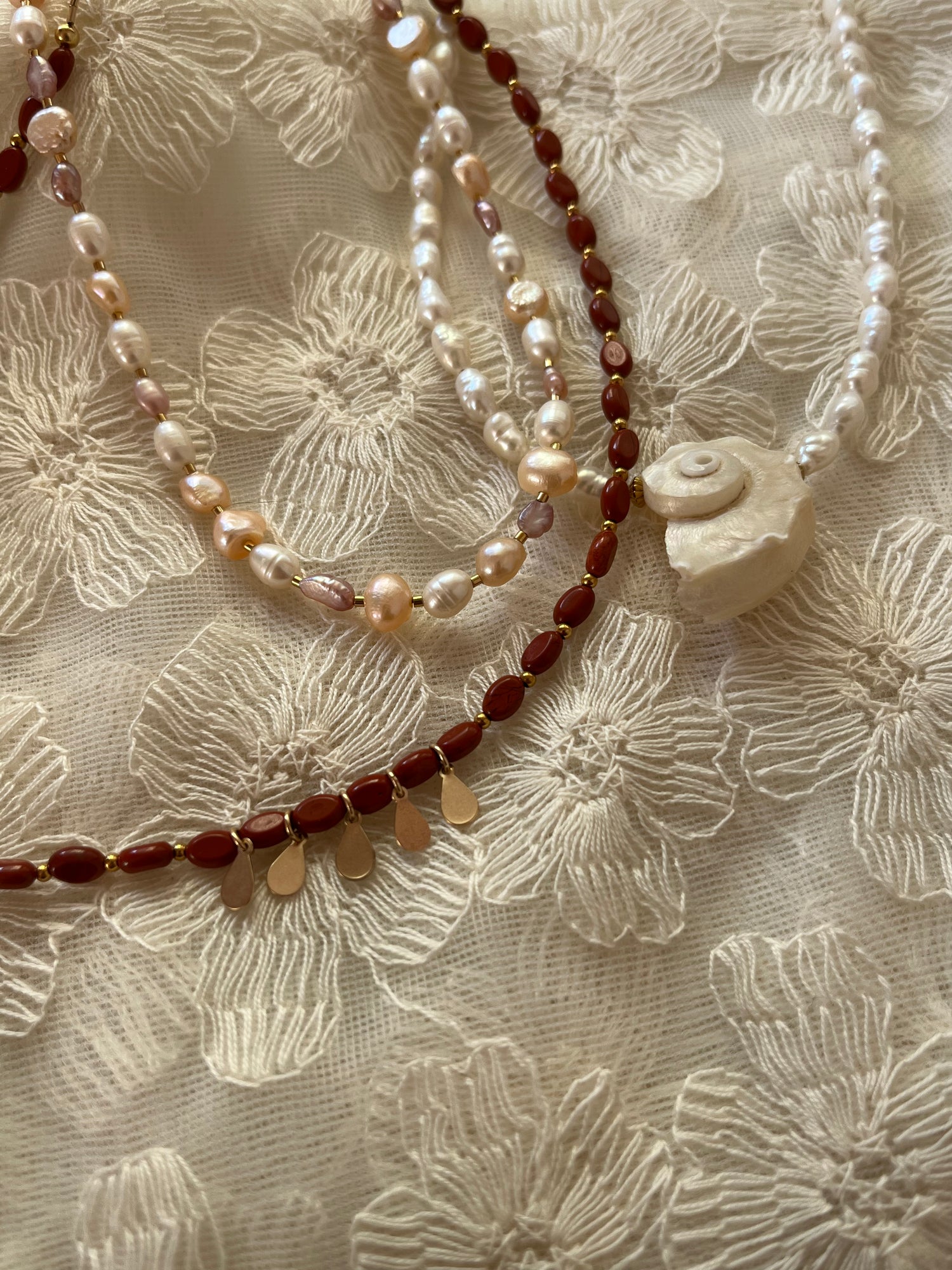 Three necklaces with beads on a floral fabric background